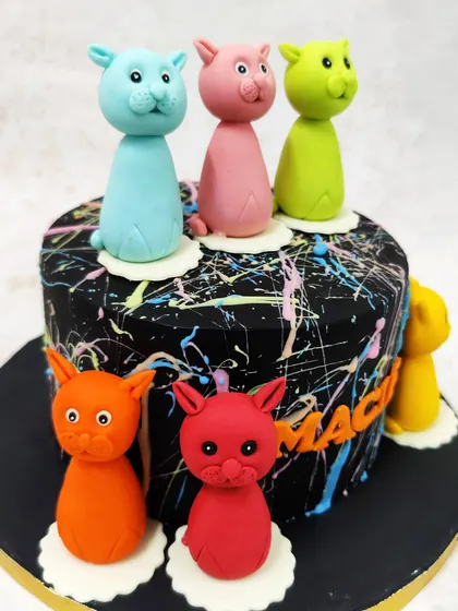 We play with color and art in this modern cat-themed cake. A dramatic black cake with neon paint splatters serves as the canvas for a parade of colorful, stylized cat figures, making it a unique and artistic choice for a cat lover.