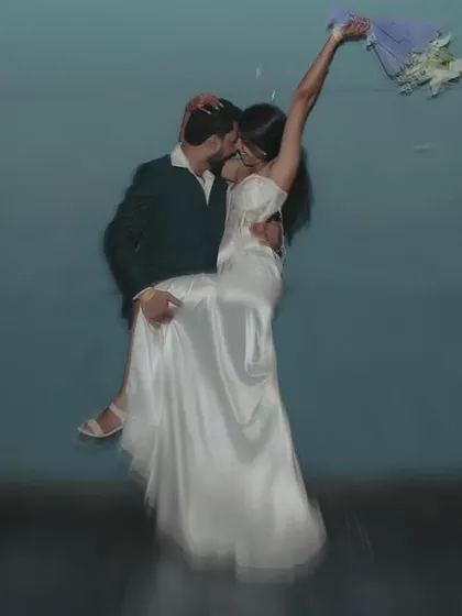 An artistic, motion-blur shot of a couple dancing, with the groom lifting the bride. The blue background adds a dreamy, surreal quality.