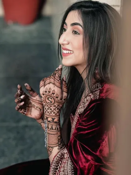 A simple yet elegant way to personalize your mehandi is with a beautifully designed initial, like the letter 'S' featured prominently on the back of the hand.