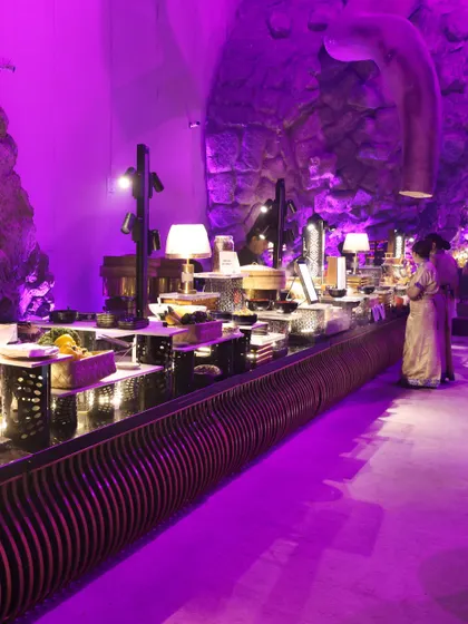 A view of our extensive buffet setup, bathed in dramatic purple lighting. We design our food stations to integrate seamlessly with the event's decor, creating a cohesive and immersive sensory experience for all guests.