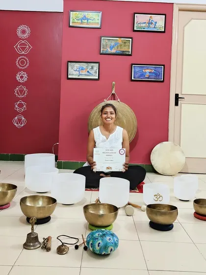 A graduate proudly displays her certificate, surrounded by the sacred instruments of sound healing. This moment marks the beginning of her fulfilling journey to share the transformative power of sound with others.