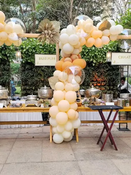 Even functional areas like buffet stations can be decorated to match the event theme. Here, I used organic balloon arches in neutral tones to frame the food service area for a large outdoor event.