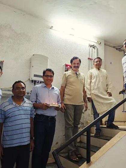 A housing society committee performs a puja for their new solar inverter system.