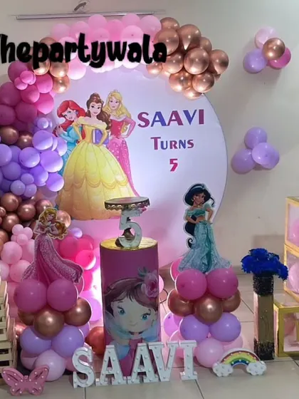 A multi-princess theme for a 5th birthday, featuring Ariel, Belle, and Jasmine. The decor includes a custom backdrop and 'BABY' blocks.