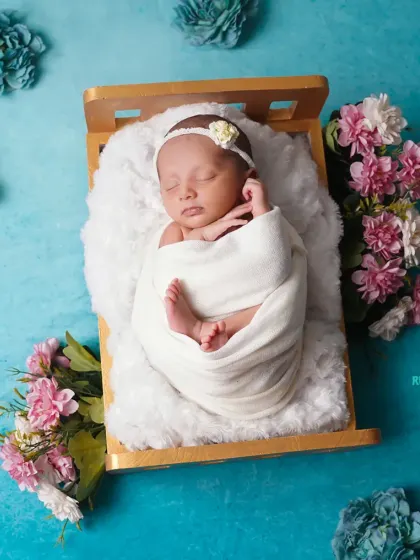 A beautifully swaddled newborn in a tiny bed, surrounded by flowers. This overhead shot showcases the symmetry and artistry of our posing.