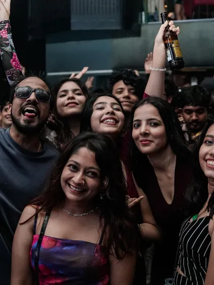 A group of friends smiling, with one holding up a beer. It's a celebration of good times.