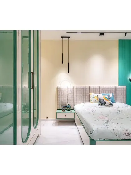 A wider view of the green and white master bedroom, showing the interplay between the fluted accent wall, the patterned headboard, and the sleek wardrobe. The track lighting provides flexible and focused illumination.