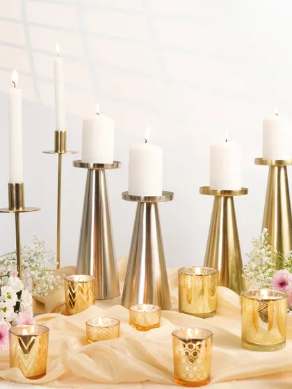 A collection of golden candle holders of various sizes, creating a warm and luxurious festive display.