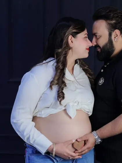 An intimate and modern couple's shot. The focus is on the bare baby bump, with the parents-to-be sharing a close moment, creating a simple yet powerful image.
