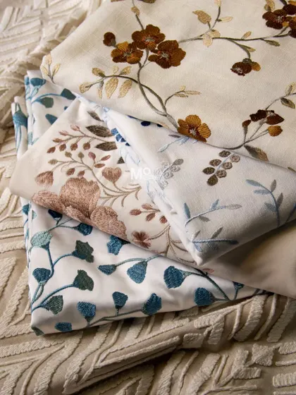 The Bloomweave Collection, featuring a harmonious blend of cotton, satin, and polyester with embroidered florals and foliage. This stack shows a variety of botanical designs in different colorways.