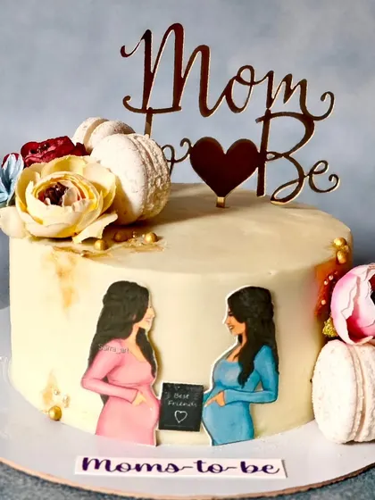 A sweet cake to celebrate two moms-to-be. This design features hand-painted portraits, macarons, and fresh flowers, making it a beautiful centerpiece for a joint baby shower.