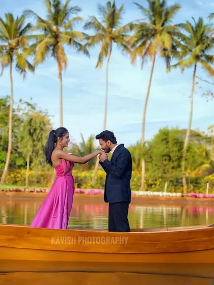 A classic romantic gesture captured on a boat, with a line of palm trees creating a beautiful, scenic backdrop for this pre-wedding shoot.