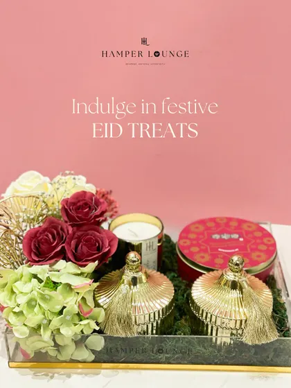 An eye-catching Eid hamper in an acrylic tray, featuring bold red and gold decorative jars. The arrangement is balanced with soft green hydrangeas and red roses, creating a rich and festive color palette.
