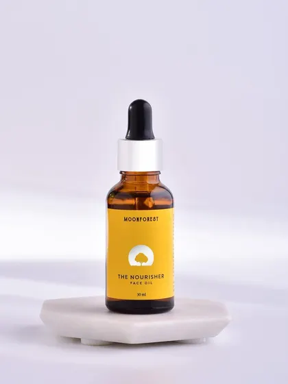 A product-centric shot of Moon Forest's face oil on a marble pedestal. The clean, bright lighting emphasizes the product's purity and quality.