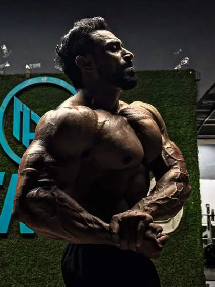 A side chest pose in the gym, showing the striations and fullness of the pectoral muscles.