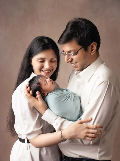A classic portrait of new parents with their baby. The soft smiles and gentle hold show the overwhelming love and wonder of this new chapter.
