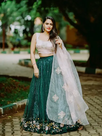 A full view of the green and pink lehenga. The floral embroidery at the hem of the skirt adds a delicate, feminine touch to this elegant party wear outfit.
