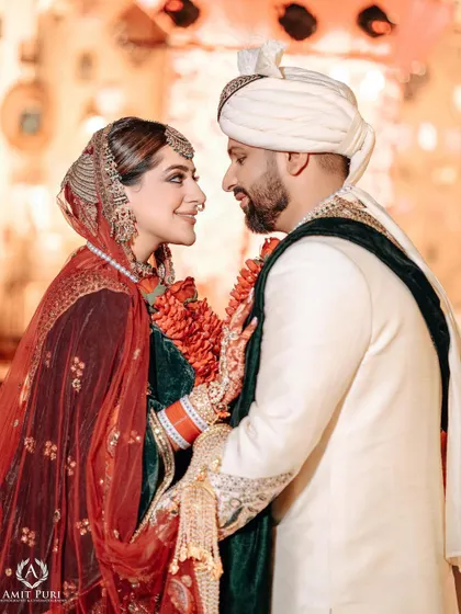A classic Jaimala moment, capturing the look of love and admiration between the bride and groom. Their traditional attire and the floral garlands add to the beauty of the scene.