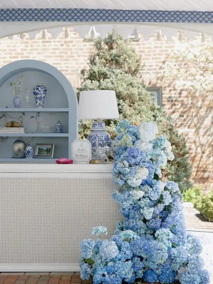 A cascading floral arrangement of blue hydrangeas flows down the side of the bar. This detail demonstrates how we integrate lush, natural elements into our structural designs for a seamless and luxurious look.