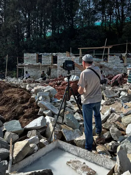 Ariel Huber navigates a field of rubble to capture the perfect shot of the emerging stone walls. Architectural photography is an art that requires a keen eye for composition, even on a chaotic construction site.