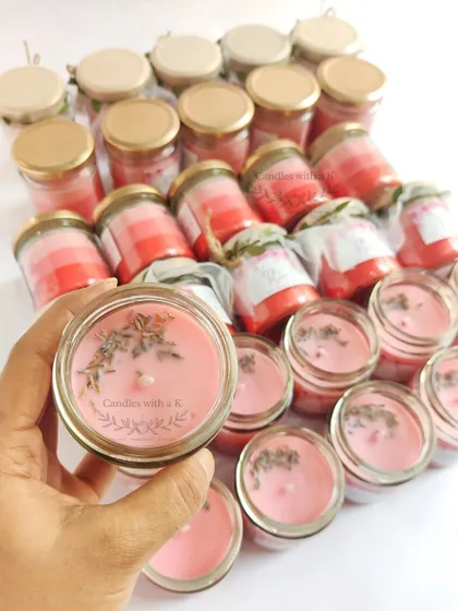 A hand holding one of the anniversary candles, showing the beautiful layers and botanical details up close.