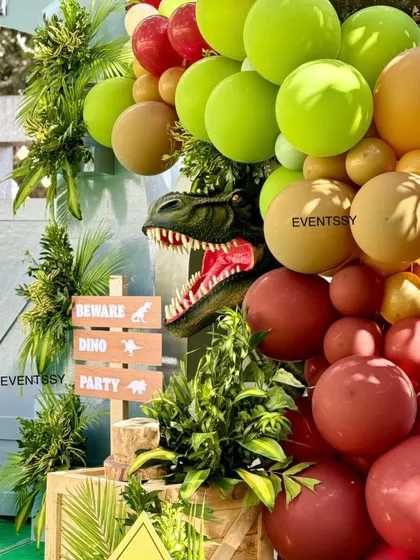 A T-Rex head emerges from a balloon garland, adding a thrilling and dynamic element to the decor.