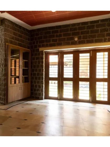 An interior view showing how the ruggedness of the stone wall is balanced by the refined finish of the wooden doors and built-in cabinetry.