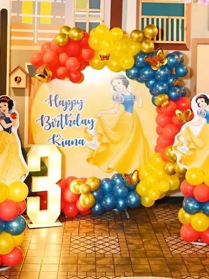 A Snow White themed birthday party for a 3-year-old. This setup includes character cutouts, a marquee number '3', and balloons in Snow White's signature red, yellow, and blue colors.