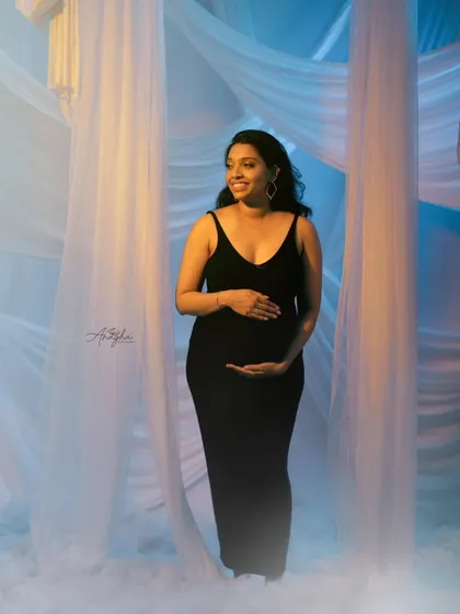 A full-length view of the dreamy, cloud-like setup in the studio. The mother-to-be looks serene and beautiful in this ethereal setting.