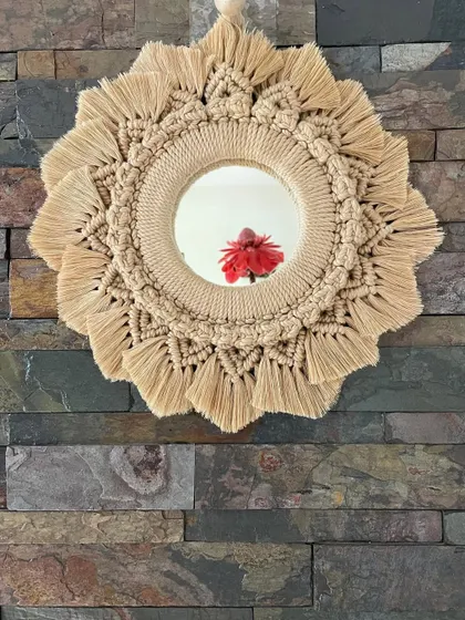 This macrame mirror in a natural, sandy beige is a classic bohemian decor piece. The intricate knotting and fringe create a beautiful frame for the mirror.