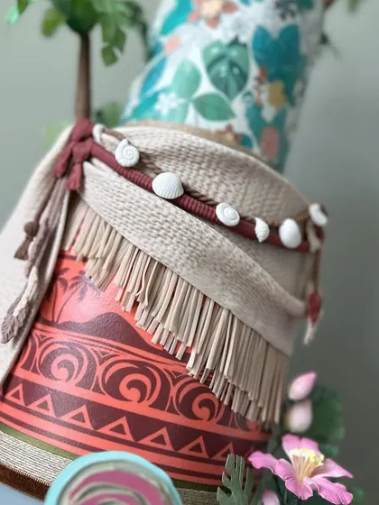 A detailed shot of the middle tier, showing the intricate fondant work used to replicate the textures of woven fabric and shells.