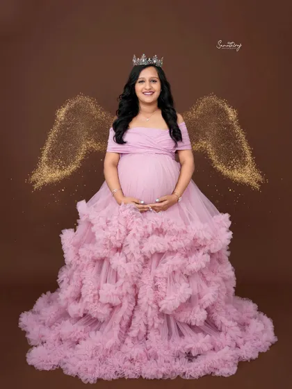 A touch of magic with this angel-themed portrait. The mother-to-be wears a pink ruffled gown and a tiara, with sparkling angel wings added for a dreamy, ethereal effect.