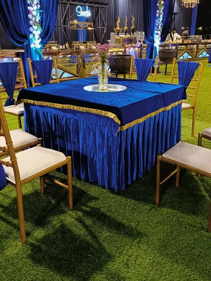Guest seating at a blue-themed engagement party, with royal blue tablecloths and elegant gold Chiavari chairs.