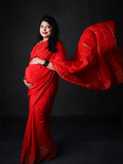 A dynamic shot of a mom-to-be in a red saree, with the pallu flowing in the air. This technique adds movement and grace to the portrait.