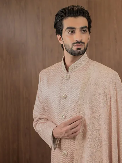 A close-up view of the rose gold sherwani, focusing on the delicate, textured embroidery and the elegant buttons that complete this classic piece of men's ethnic wear.