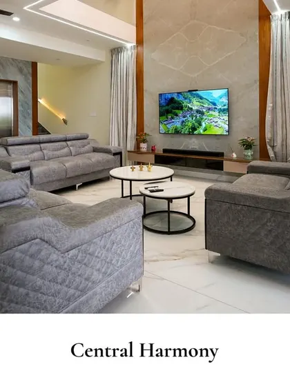 A harmonious living space where plush grey sofas are arranged for conversation, set against a backdrop of high ceilings and a striking double-height accent wall, creating a sense of grandeur.