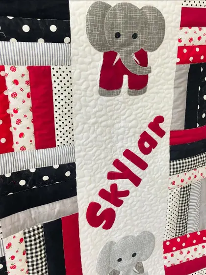 A close-up of the "Skylar" quilt, showing the detailed elephant and name appliqué.