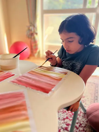 The focus and precision of a young artist. Watercolor painting is a fantastic way for children to learn about color blending and water control.