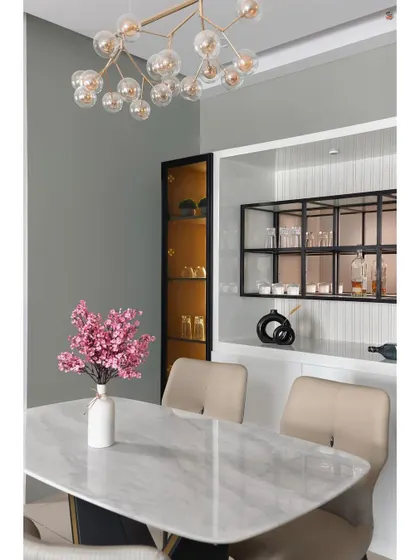 A closer look at a sophisticated dining setup. The combination of a white marble table, a modern bubble chandelier, and a sleek, built-in bar unit with internal lighting creates an atmosphere of refined luxury.