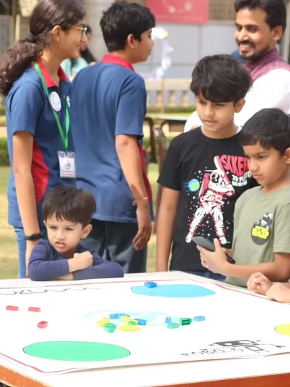 Students gather around a robotics table at an outdoor orientation event for the IRO. We make learning about robotics accessible and exciting for children of all ages.