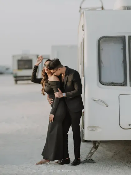 A passionate and playful moment as the groom kisses the bride's neck while she waves happily, captured during their desert pre-wedding shoot.