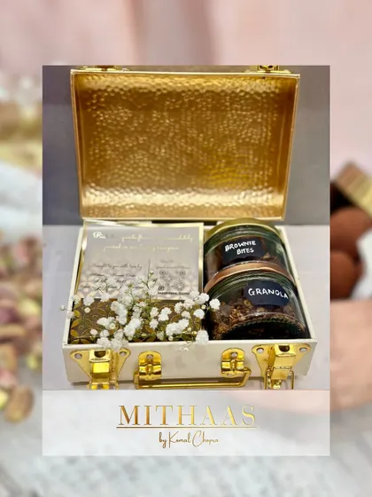 For a touch of modern luxury, I offer these hammered gold-finish metal briefcases. This one is packed with brownie bites and granola, adorned with baby's breath for a delicate contrast.
