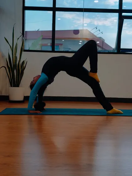 Charvi practices a one-legged wheel pose, an advanced variation that requires significant strength, balance, and flexibility. We are so proud of her progress.