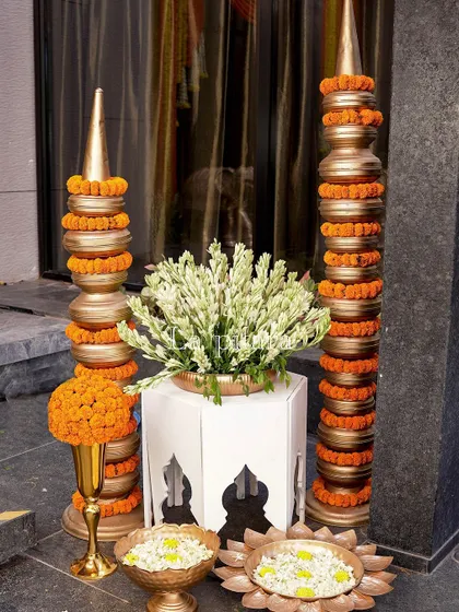 Decorative pillars wrapped in marigold garlands stand beside an arrangement of white tuberoses. These elements were placed along pathways to guide guests and add layers to the festive decor.