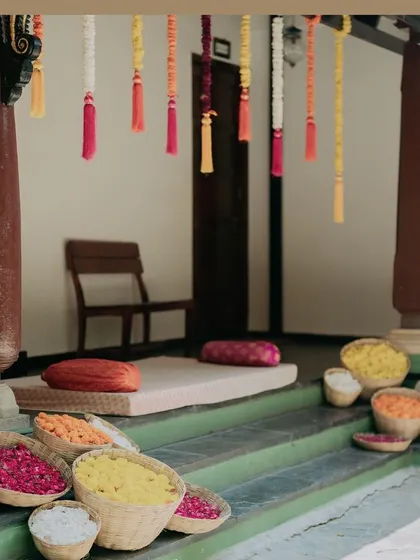 Baskets filled with colorful flower petals are placed along the steps, ready for guests to shower the couple with blessings during the Haldi.