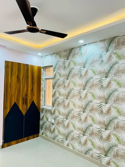 This bedroom uses a bold, tropical-themed wallpaper on one wall to create a vibrant feature. The dual-tone wardrobe complements the natural theme.