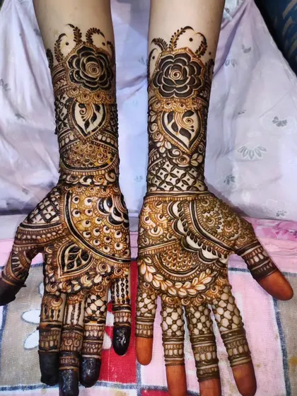 This bridal design features a bold rose motif at the wrist, surrounded by intricate patterns and shaded leaves.
