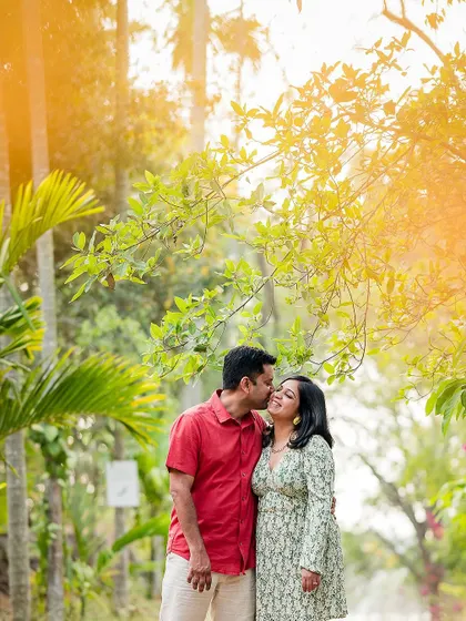 A sweet kiss on the cheek during a pre-wedding shoot in a lush, green park. These sessions are perfect for capturing your love in a relaxed environment.