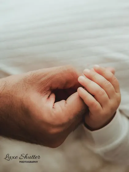 A five-month-old's hand gently holding onto their father's finger. It shows how that bond, and their grip, grows stronger over time.
