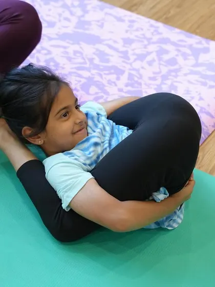 This young girl is in Yoganidrasana, or Yogic Sleep Pose. It's an advanced posture that requires deep hip and hamstring flexibility, and she makes it look effortless.
